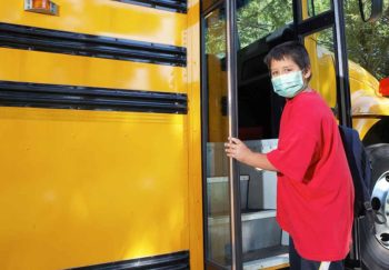young boy getting onto school bus