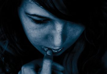 teen girl with her head lowered, hands touching face