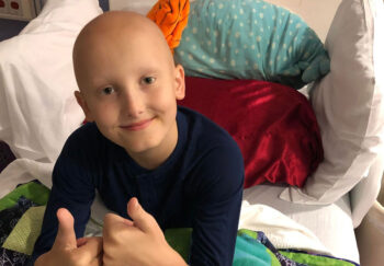 Benny gives a thumb's up. A year after his child's cancer diagnosis, this dad reflects.