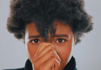 Black woman pulls down strand of natural hair
